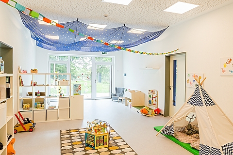 Bunt gestalteter Raum mit Spielzeugen, Zelt und Büchern